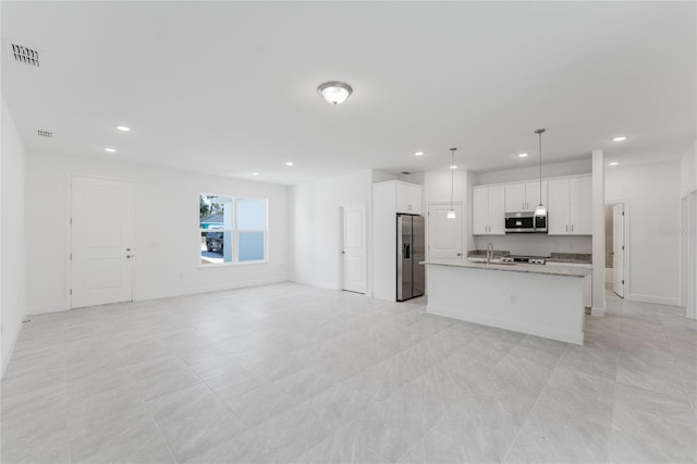 kitchen featuring stainless steel appliances, sink, hanging light fixtures, a kitchen island with sink, and white cabinets