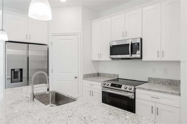 kitchen with decorative light fixtures, white cabinets, sink, and stainless steel appliances