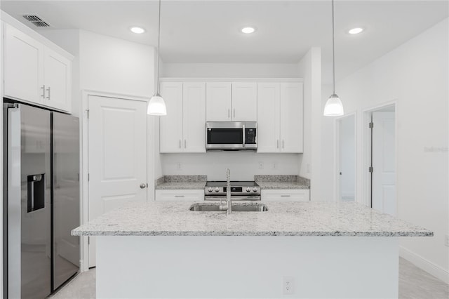 kitchen with stainless steel appliances, white cabinetry, pendant lighting, sink, and an island with sink