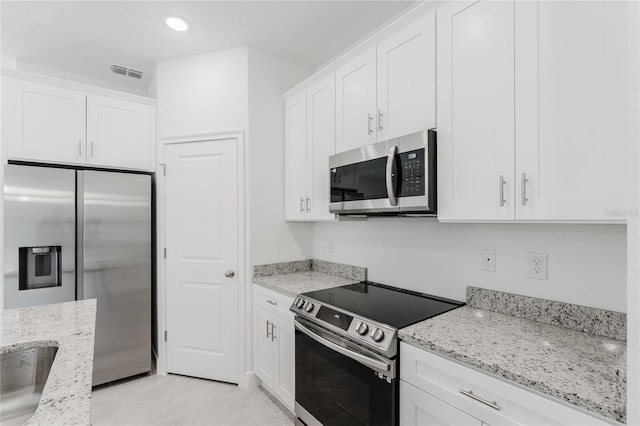 kitchen with white cabinetry, appliances with stainless steel finishes, and light stone counters