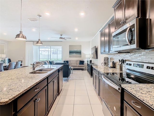 kitchen featuring light stone counters, pendant lighting, stainless steel appliances, ceiling fan, and sink