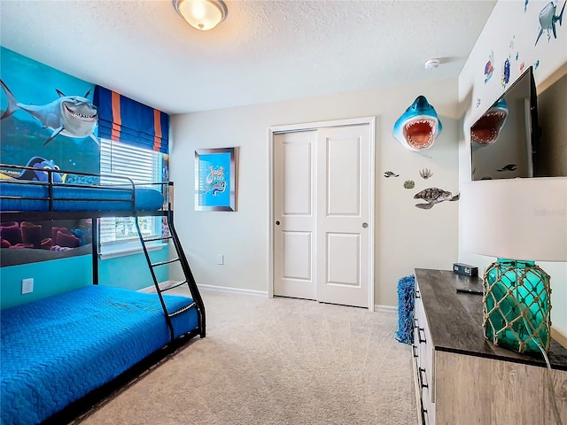 bedroom with a textured ceiling, light carpet, and a closet