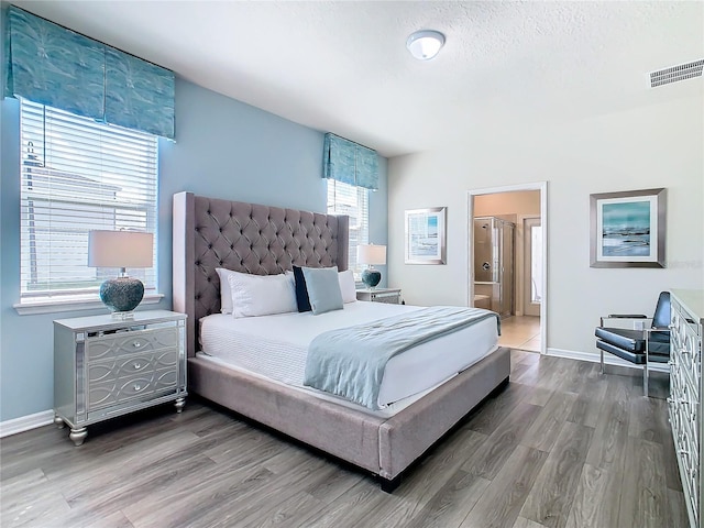 bedroom featuring hardwood / wood-style flooring, connected bathroom, and a textured ceiling