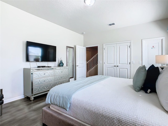 bedroom with a textured ceiling, dark wood-type flooring, and a closet