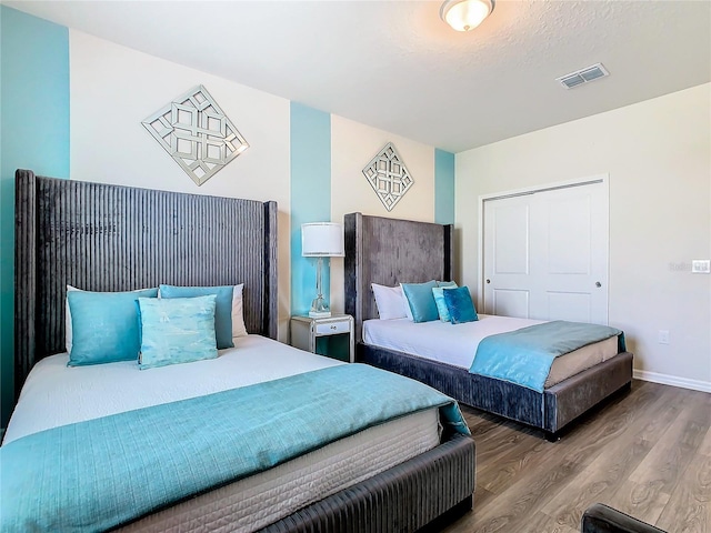 bedroom with a textured ceiling and wood-type flooring