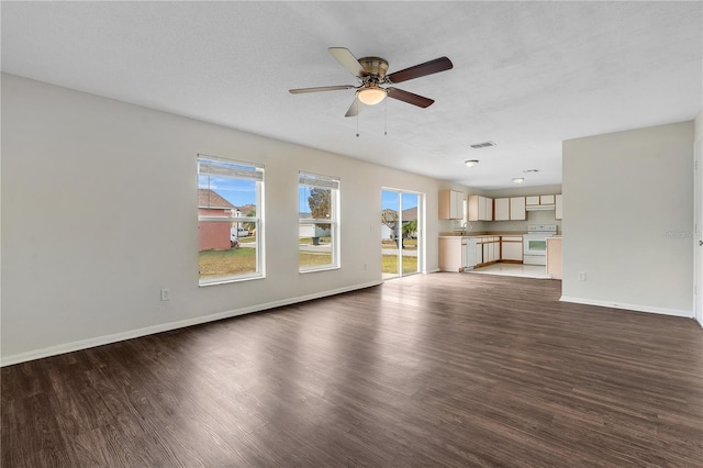 unfurnished living room with ceiling fan, dark hardwood / wood-style floors, sink, and a textured ceiling