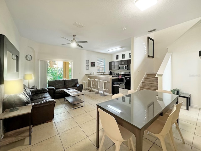 tiled dining area with a textured ceiling, sink, and ceiling fan