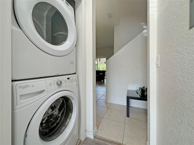 laundry area featuring stacked washer / dryer and light tile patterned floors