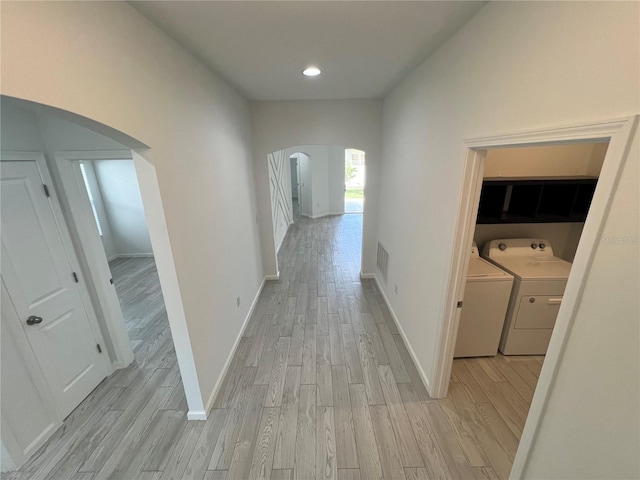 hall with washing machine and dryer and light wood-type flooring