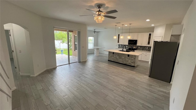 kitchen with white cabinets, hanging light fixtures, ceiling fan, appliances with stainless steel finishes, and tasteful backsplash