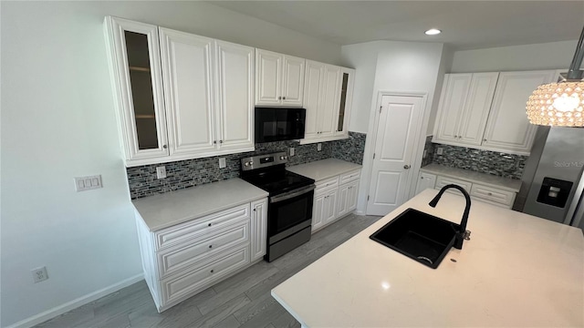 kitchen with range with electric stovetop, tasteful backsplash, sink, and white cabinets