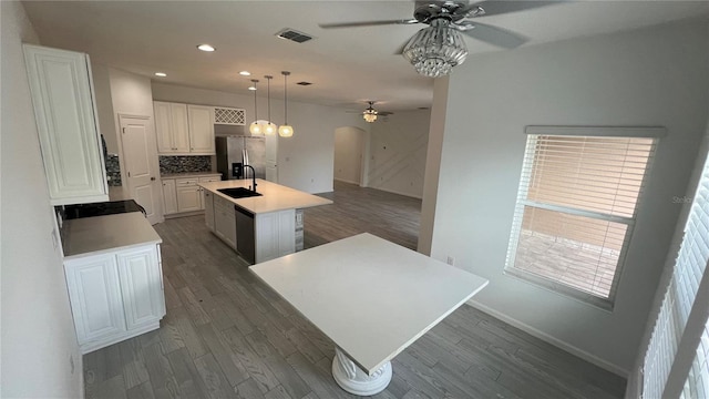 kitchen featuring dark hardwood / wood-style flooring, sink, decorative light fixtures, white cabinets, and an island with sink