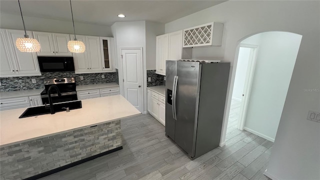 kitchen featuring white cabinets, pendant lighting, light wood-type flooring, and stainless steel appliances