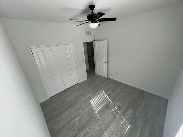 unfurnished bedroom featuring a closet, hardwood / wood-style flooring, ceiling fan, and lofted ceiling