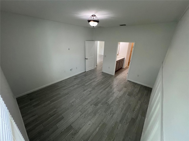 unfurnished bedroom featuring ensuite bath and dark hardwood / wood-style floors