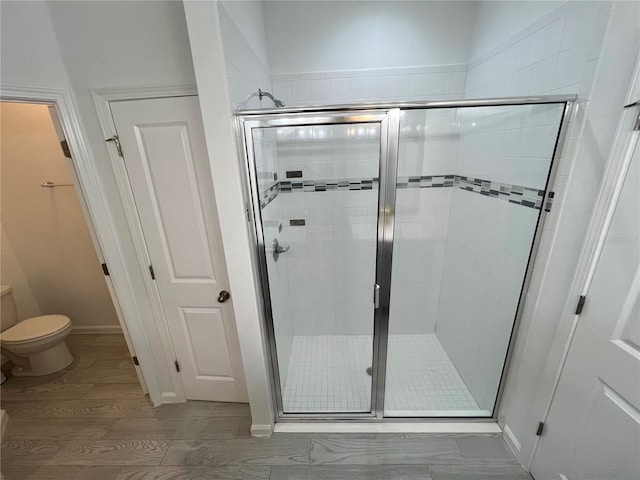 bathroom with wood-type flooring, toilet, and an enclosed shower