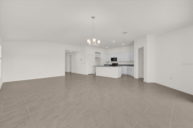 unfurnished living room with a chandelier, light tile patterned flooring, and sink