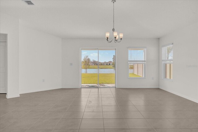 interior space featuring a water view, light tile patterned floors, and a chandelier