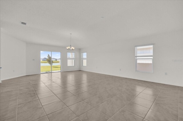 unfurnished room with a notable chandelier and light tile patterned flooring