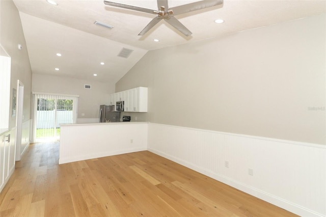 empty room with ceiling fan, lofted ceiling, and light wood-type flooring