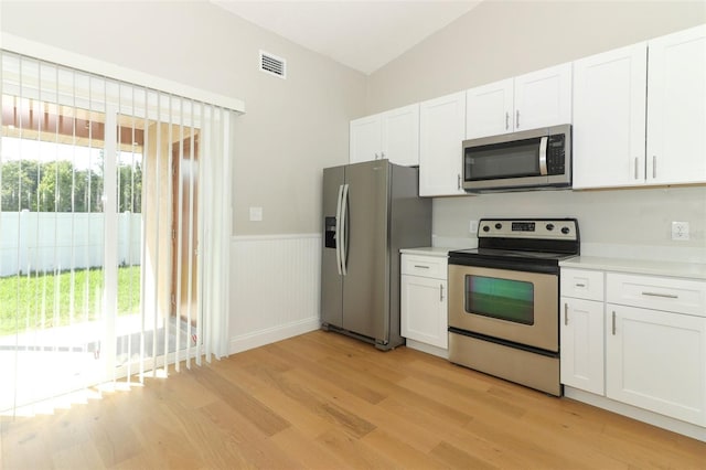 kitchen with lofted ceiling, light wood-type flooring, white cabinetry, and appliances with stainless steel finishes