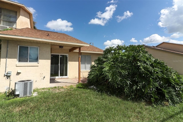 rear view of house featuring central AC unit and a lawn