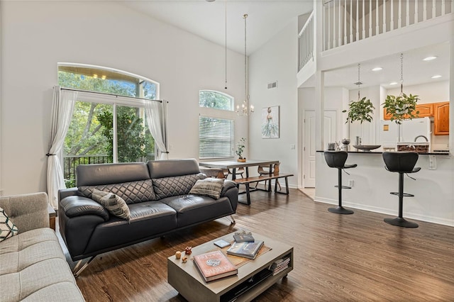 living room with a notable chandelier, a high ceiling, and dark wood-type flooring