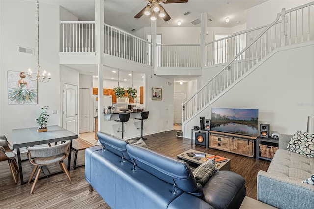 living room with ceiling fan with notable chandelier, hardwood / wood-style floors, and high vaulted ceiling