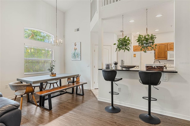 kitchen featuring a kitchen breakfast bar, white appliances, hardwood / wood-style floors, and decorative light fixtures