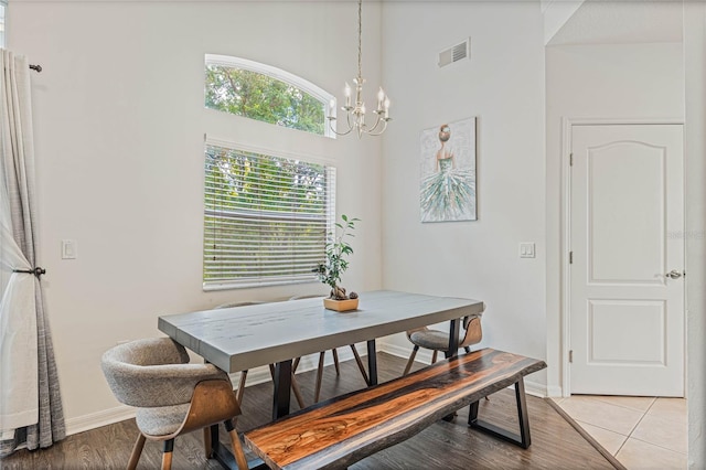 tiled dining area featuring a notable chandelier and a towering ceiling