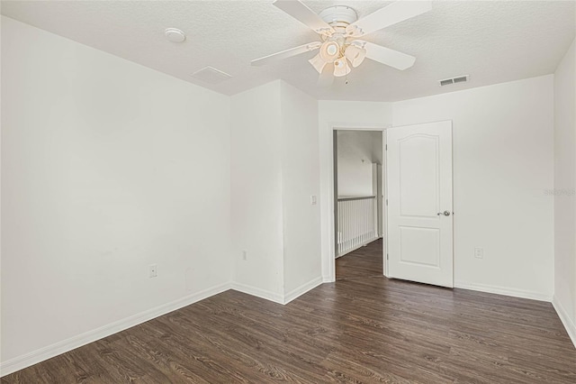 spare room with a textured ceiling, ceiling fan, and dark wood-type flooring