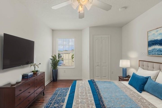 bedroom with ceiling fan, a closet, dark wood-type flooring, and a textured ceiling