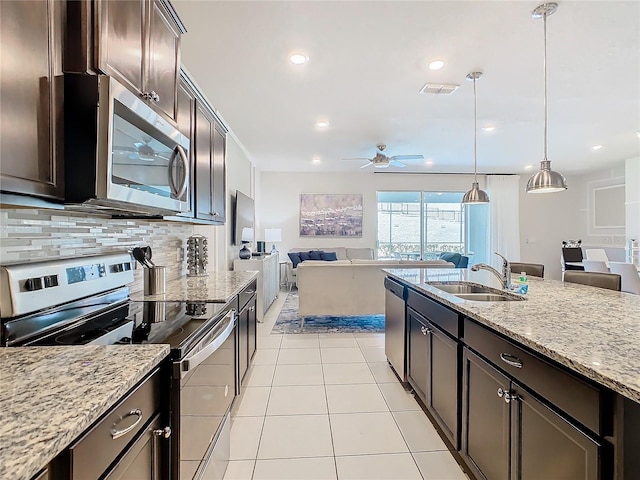 kitchen featuring ceiling fan, light stone counters, decorative light fixtures, backsplash, and appliances with stainless steel finishes