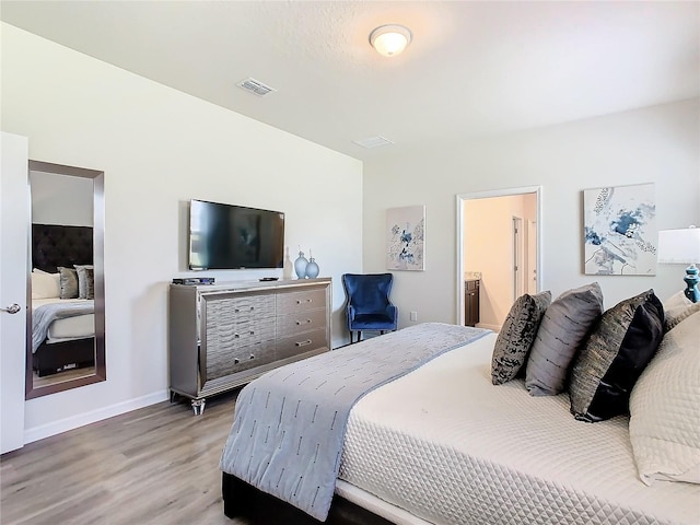 bedroom with ensuite bath and light hardwood / wood-style flooring