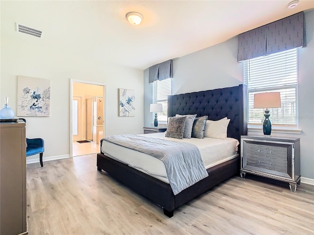 bedroom featuring connected bathroom and light hardwood / wood-style floors