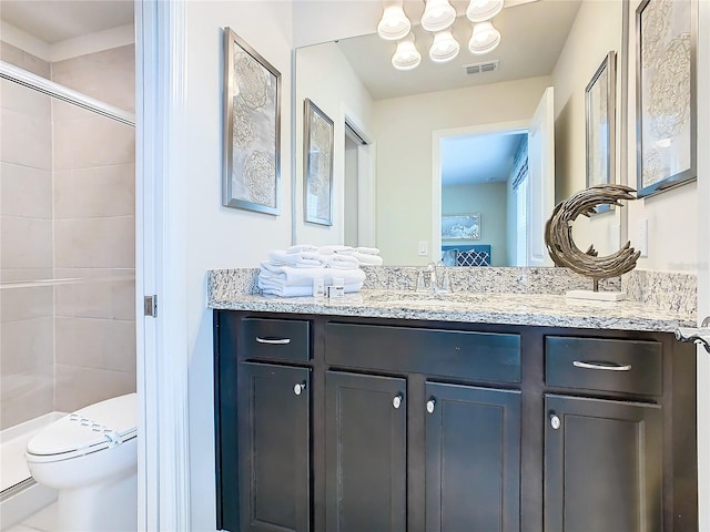 bathroom with a shower with shower door, vanity, and toilet