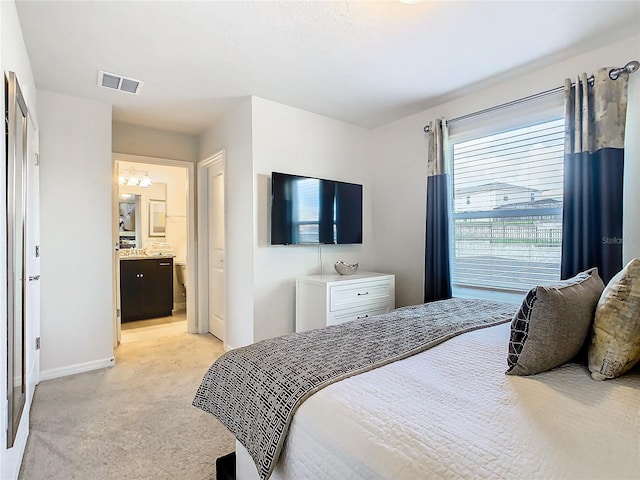 bedroom with light colored carpet and ensuite bathroom