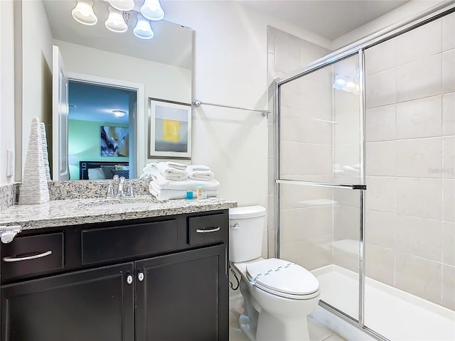 bathroom featuring vanity, toilet, and a shower with door