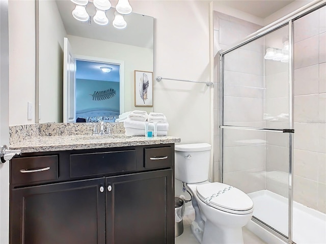 bathroom featuring a shower with door, vanity, and toilet