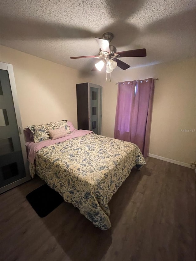 bedroom with ceiling fan, a textured ceiling, and dark wood-type flooring