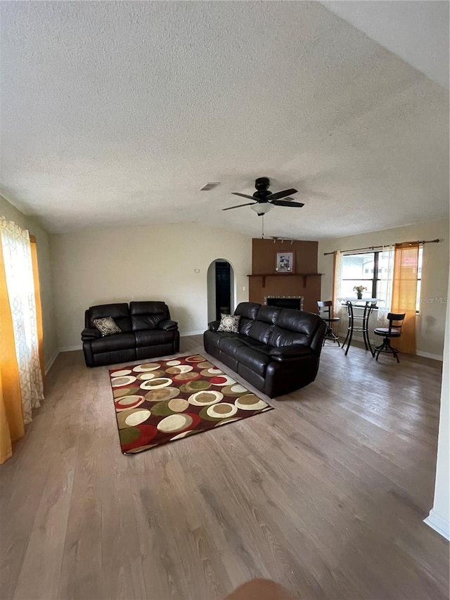 living room featuring wood-type flooring, a textured ceiling, and ceiling fan