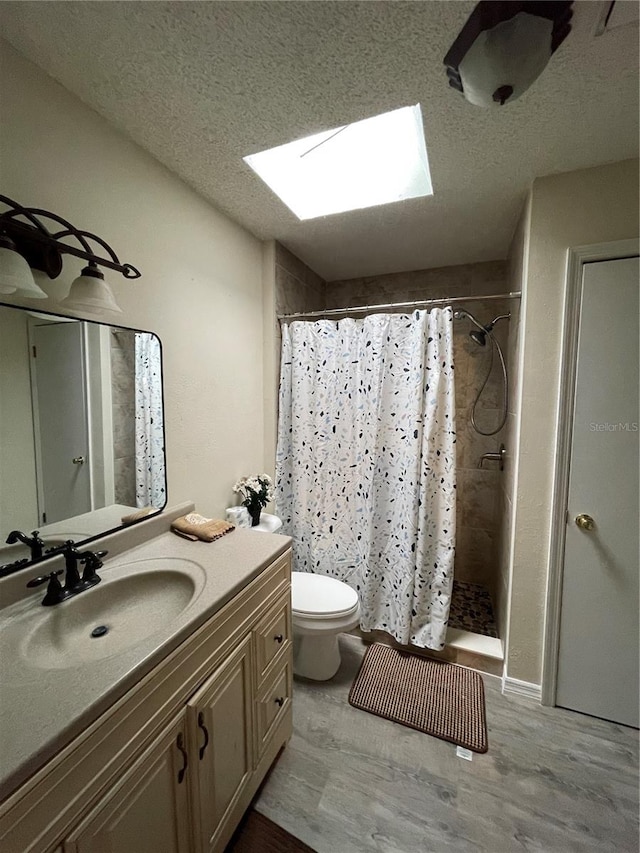 bathroom with vanity, wood-type flooring, a skylight, toilet, and a shower with curtain