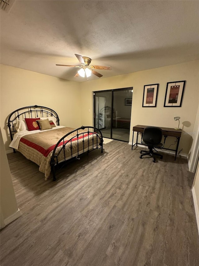 bedroom with ceiling fan, a textured ceiling, and dark hardwood / wood-style floors