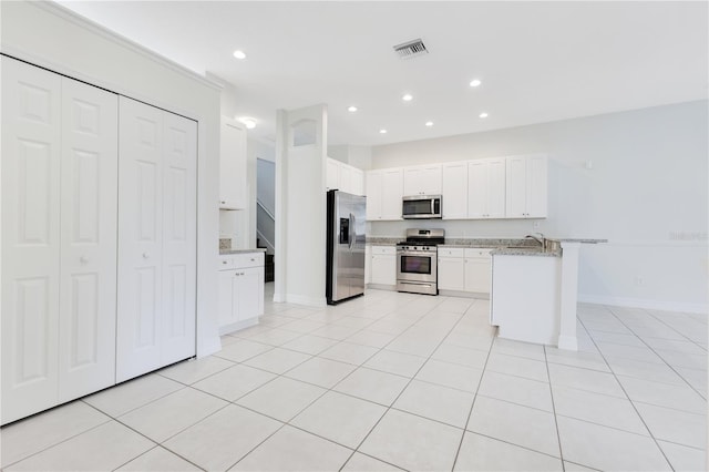 kitchen featuring light stone countertops, stainless steel appliances, white cabinetry, and light tile patterned flooring