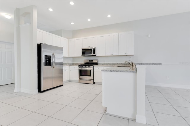 kitchen with white cabinetry, light stone countertops, kitchen peninsula, and appliances with stainless steel finishes