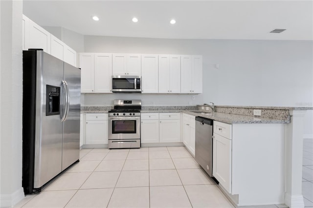 kitchen featuring light stone countertops, stainless steel appliances, white cabinetry, and sink