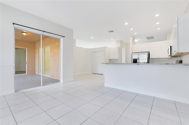 kitchen with white cabinets, stainless steel appliances, light stone countertops, and light tile patterned flooring