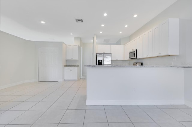 kitchen featuring kitchen peninsula, appliances with stainless steel finishes, light stone countertops, light tile patterned floors, and white cabinets