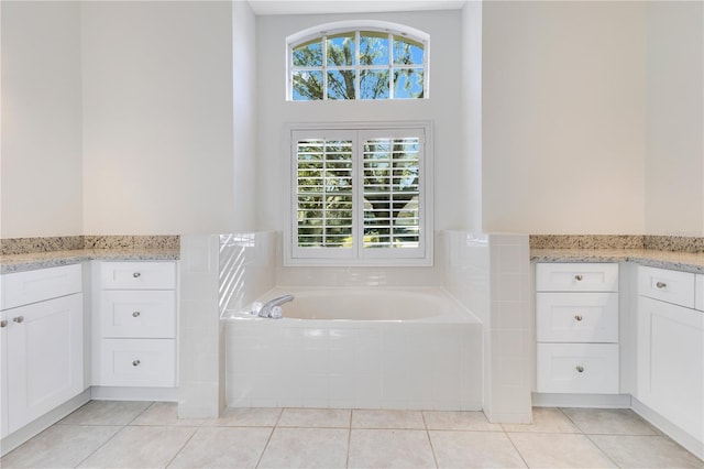 bathroom featuring tile patterned flooring, vanity, and tiled bath