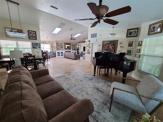 tiled living room with ceiling fan with notable chandelier and lofted ceiling with skylight